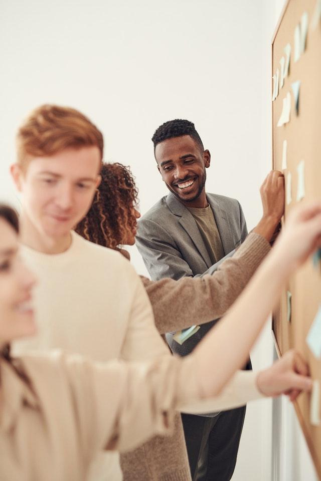 Office workers looking at post-its on wall